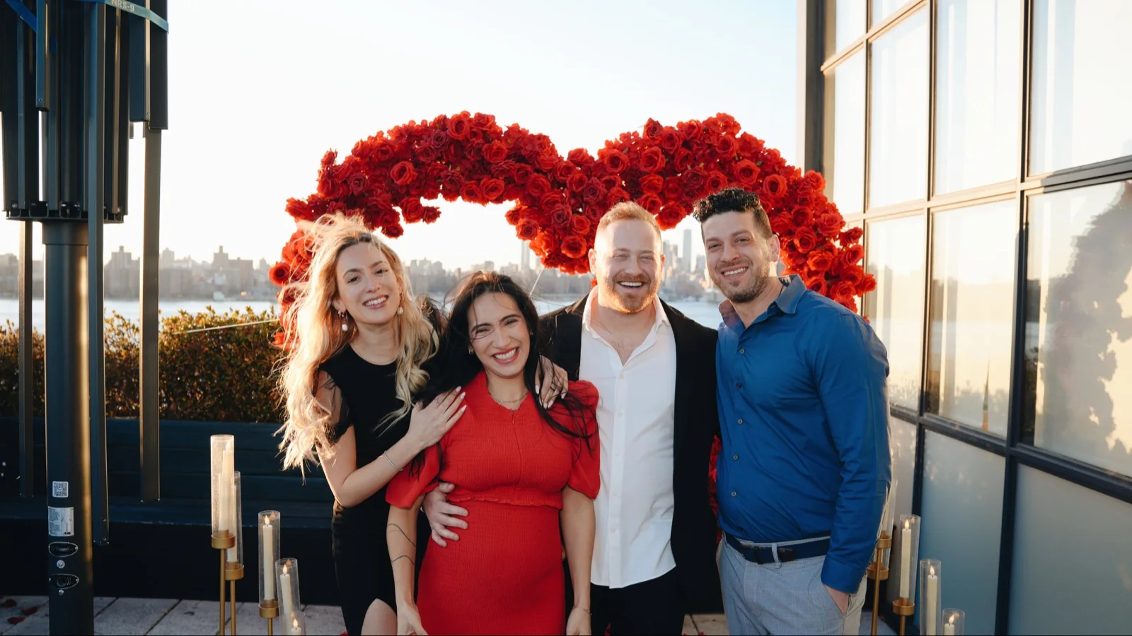 Four guests posing together in front of a red floral arrangement