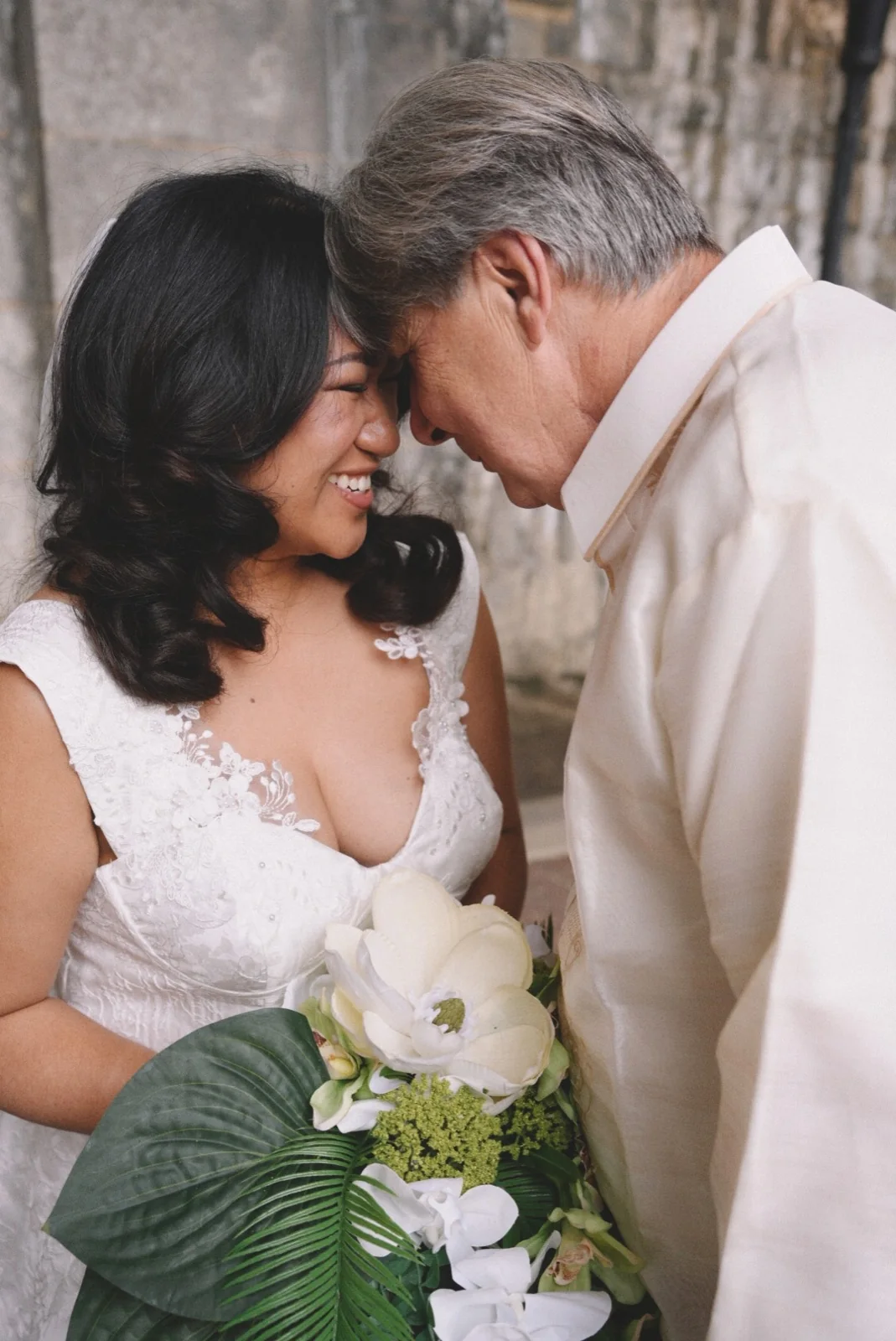 A newlywed couple resting their foreheads together and smiling